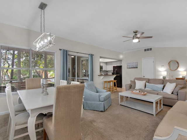 living room featuring light carpet and ceiling fan with notable chandelier