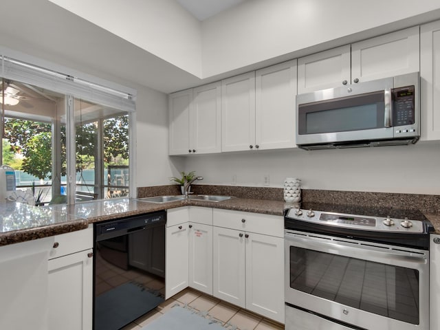 kitchen featuring appliances with stainless steel finishes, sink, white cabinets, dark stone counters, and light tile patterned floors