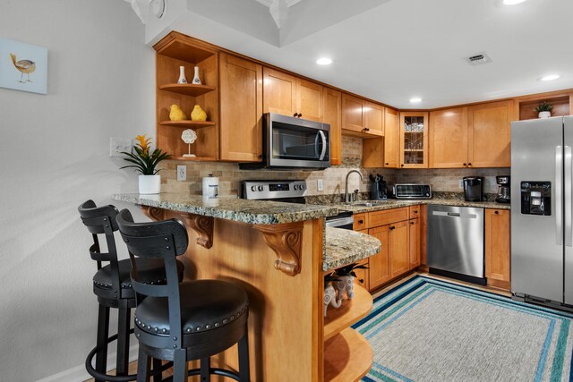 kitchen featuring sink, appliances with stainless steel finishes, backsplash, a kitchen breakfast bar, and kitchen peninsula