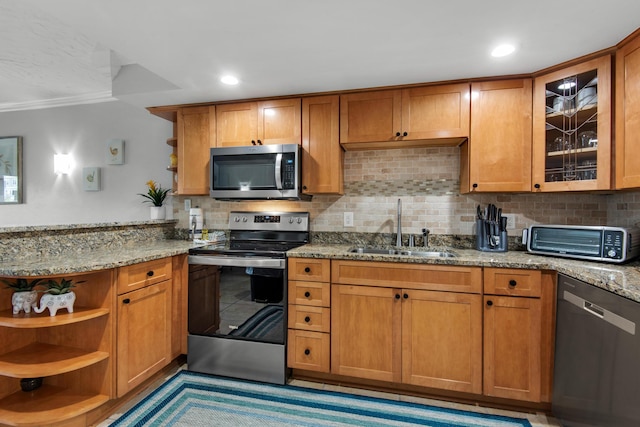 kitchen with sink, light stone counters, ornamental molding, appliances with stainless steel finishes, and decorative backsplash