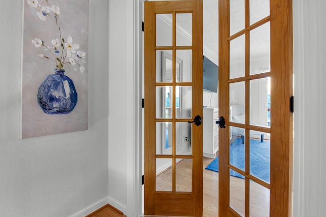 interior space with french doors, wood-type flooring, and crown molding