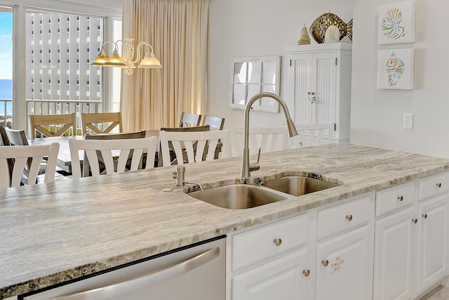 kitchen featuring pendant lighting, sink, light stone counters, white cabinets, and stainless steel dishwasher