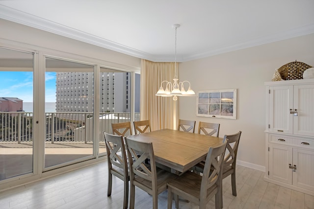 dining space featuring crown molding, an inviting chandelier, and light wood-type flooring