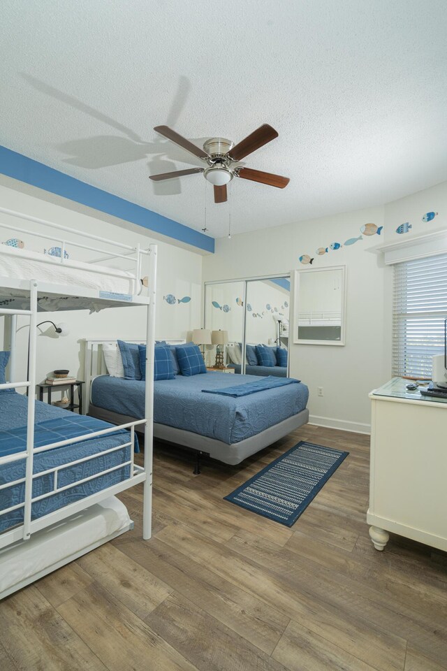 bedroom with ceiling fan, a textured ceiling, and dark hardwood / wood-style flooring