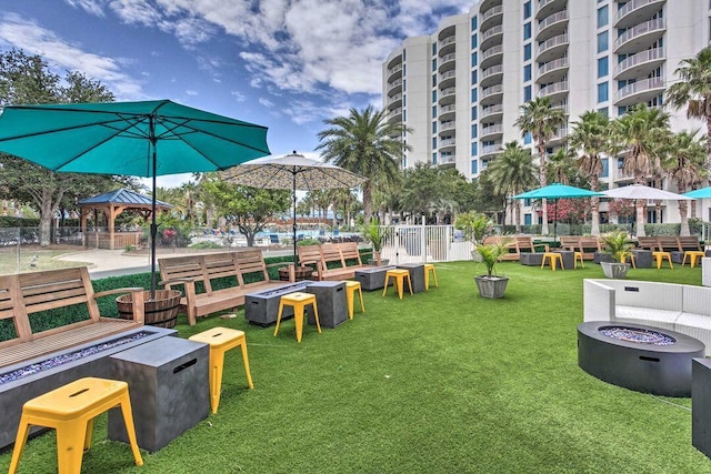 view of community featuring a lawn, an outdoor fire pit, and a gazebo