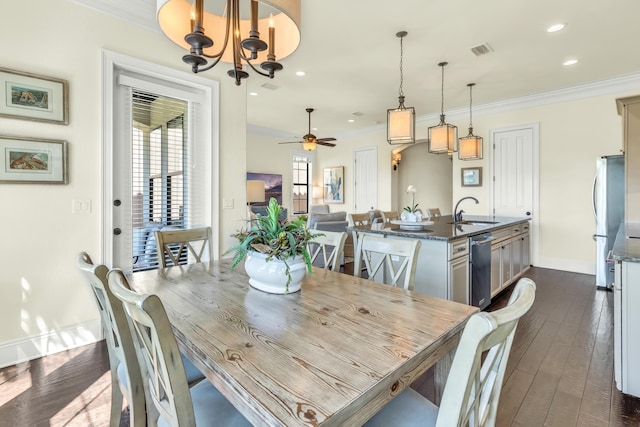 dining area with sink, ceiling fan with notable chandelier, dark wood-type flooring, and ornamental molding