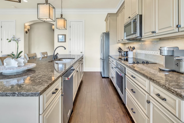 kitchen featuring pendant lighting, sink, appliances with stainless steel finishes, a kitchen breakfast bar, and dark stone counters