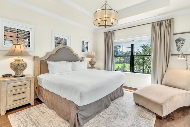 bedroom featuring hardwood / wood-style flooring, ornamental molding, and a notable chandelier