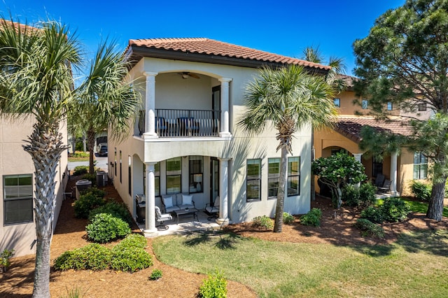 rear view of property featuring a balcony, a yard, cooling unit, and ceiling fan