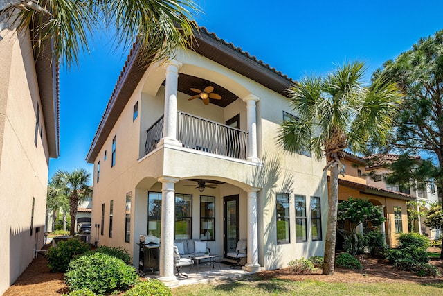 rear view of property with an outdoor living space, a patio, a balcony, and ceiling fan