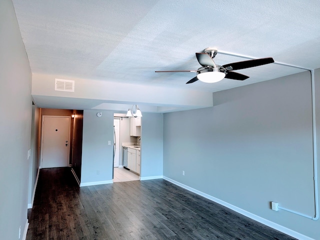 unfurnished living room featuring ceiling fan, a textured ceiling, and wood-type flooring