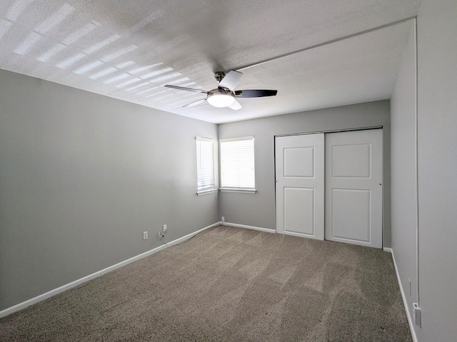 unfurnished bedroom featuring ceiling fan, a textured ceiling, a closet, and carpet flooring