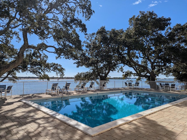 view of swimming pool featuring a water view and a patio area