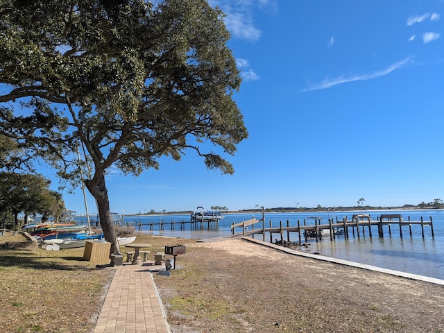 dock area with a water view and a yard