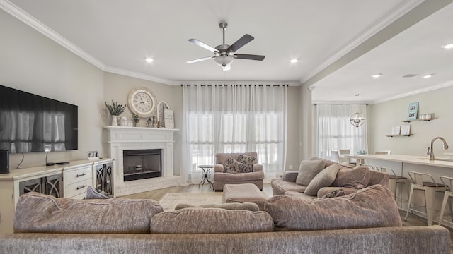 living room featuring a brick fireplace, a healthy amount of sunlight, sink, and light wood-type flooring