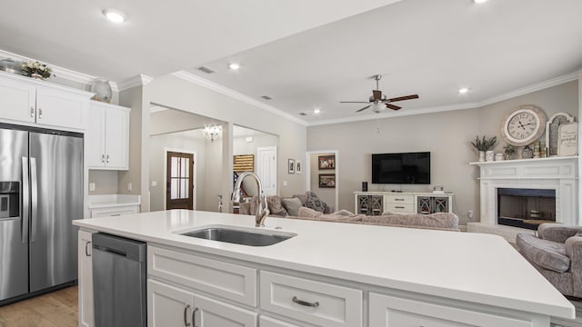 kitchen with appliances with stainless steel finishes, sink, white cabinets, a kitchen island with sink, and light wood-type flooring