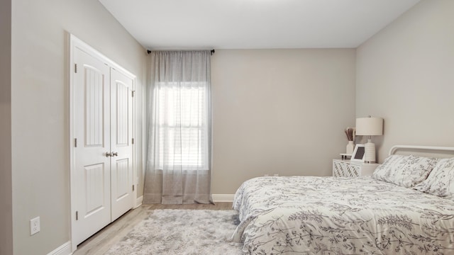 bedroom with multiple windows, a closet, and light wood-type flooring