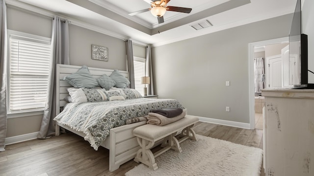 bedroom with multiple windows, a raised ceiling, ceiling fan, and light hardwood / wood-style floors