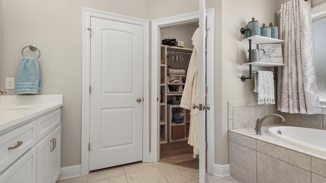 bathroom featuring vanity, tile patterned flooring, and tiled tub