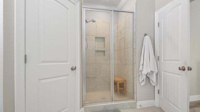 bathroom featuring tile patterned floors, ornamental molding, and a shower with shower door