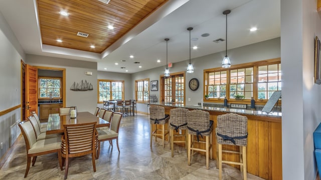 dining space with a raised ceiling, indoor bar, and wooden ceiling