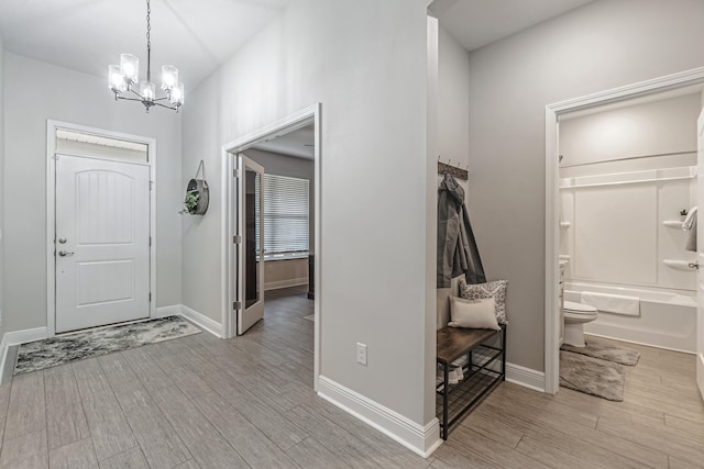 foyer entrance with light hardwood / wood-style floors and a chandelier