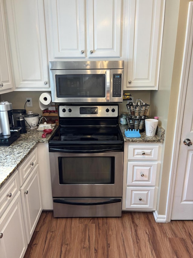 kitchen featuring white cabinetry, stainless steel appliances, light stone countertops, and hardwood / wood-style flooring