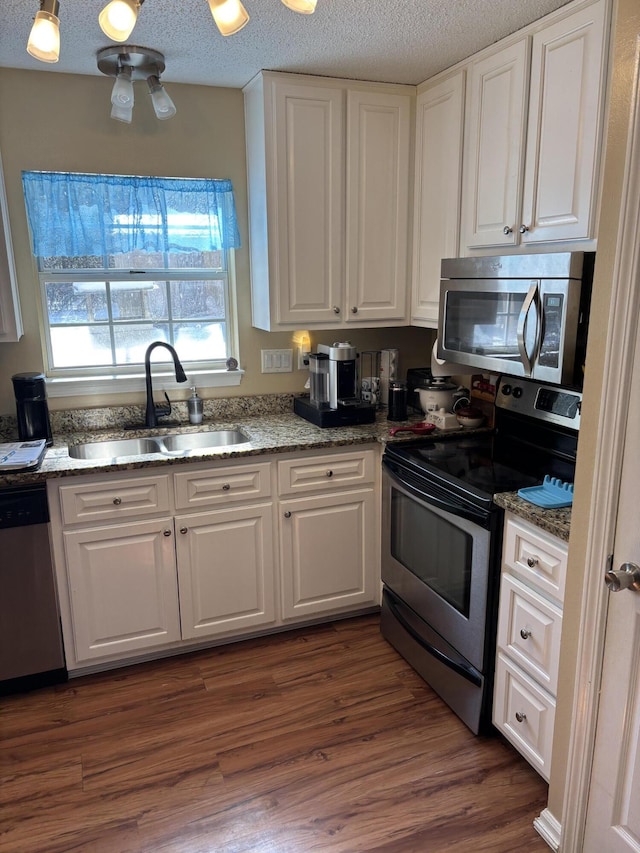 kitchen with white cabinetry, sink, light stone counters, and appliances with stainless steel finishes