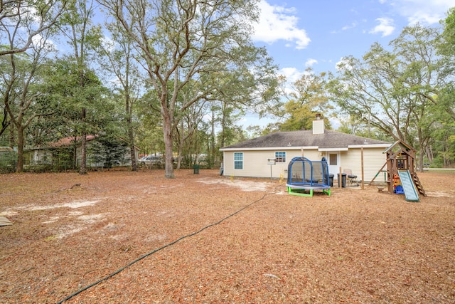 rear view of house featuring a playground and a trampoline