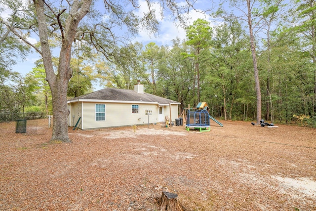 rear view of house featuring a trampoline, cooling unit, and a playground