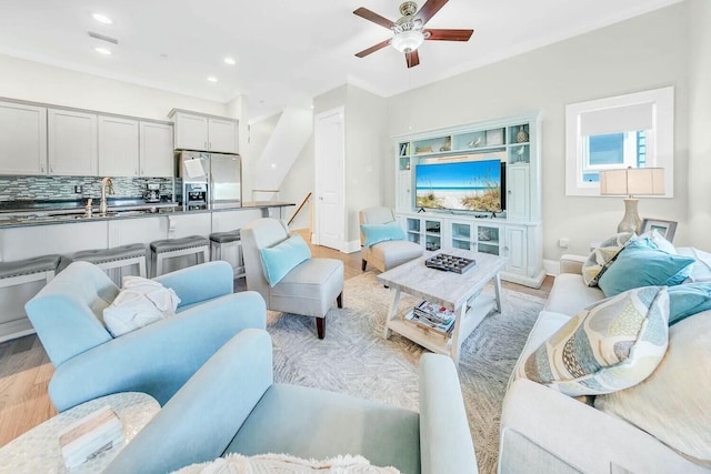 living room featuring ceiling fan, sink, and light hardwood / wood-style floors