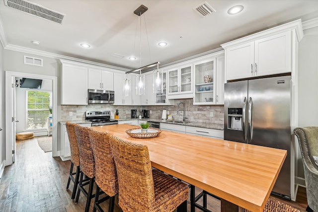 kitchen with sink, white cabinetry, a center island, appliances with stainless steel finishes, and pendant lighting