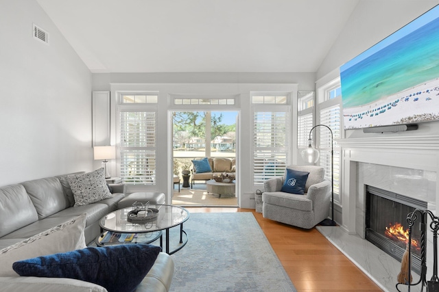 living room with a premium fireplace, vaulted ceiling, and light hardwood / wood-style flooring