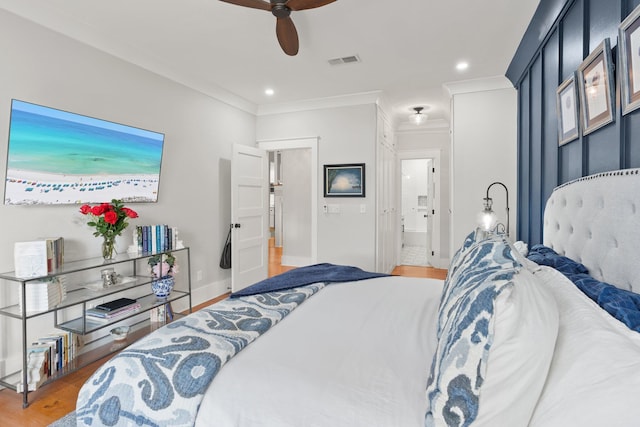 bedroom featuring hardwood / wood-style flooring, ornamental molding, ceiling fan, and ensuite bath