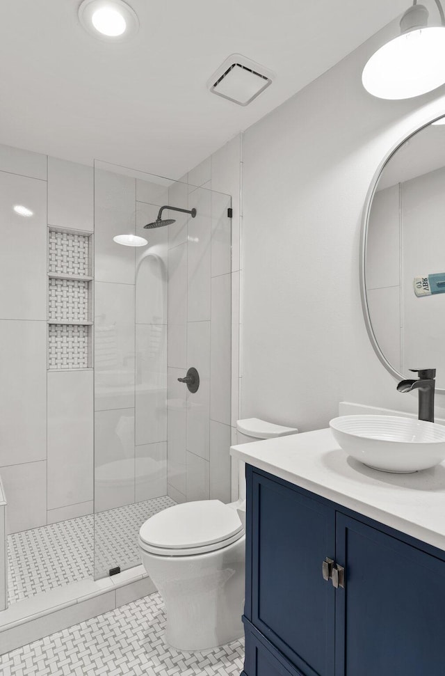 bathroom with tile patterned floors, vanity, toilet, and a tile shower