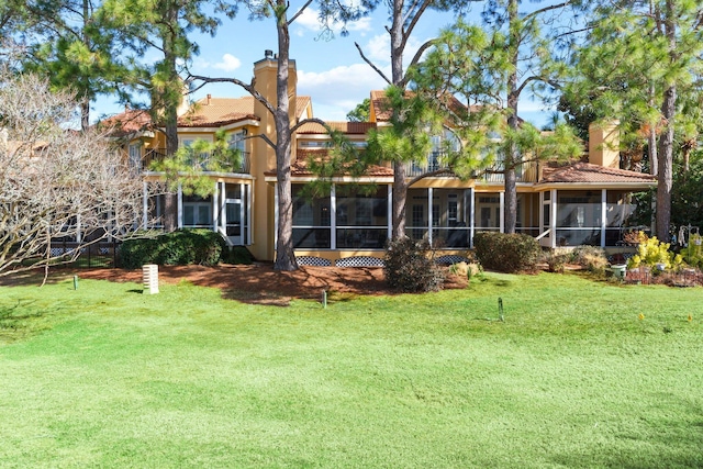 rear view of house with a sunroom and a lawn