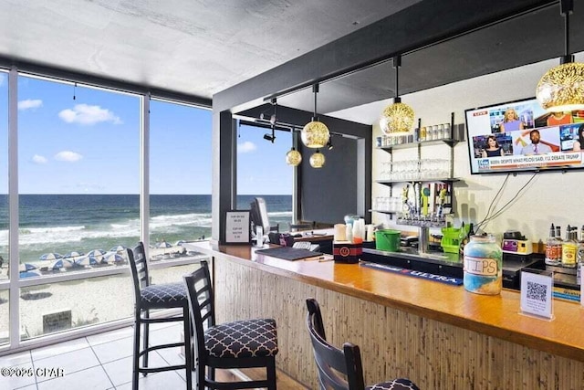 bar with decorative light fixtures, tile patterned floors, floor to ceiling windows, and a water view