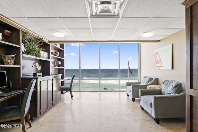 office with expansive windows, a water view, a beach view, and a drop ceiling