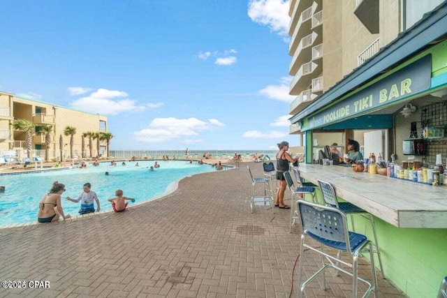 view of pool featuring a bar and a water view