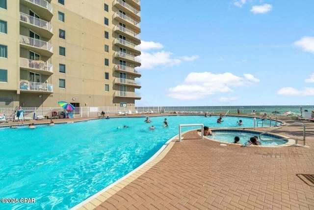 view of swimming pool with a water view, a hot tub, and a patio