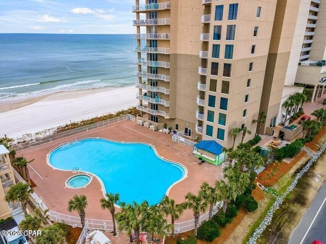 view of swimming pool featuring a water view, a patio area, and a view of the beach