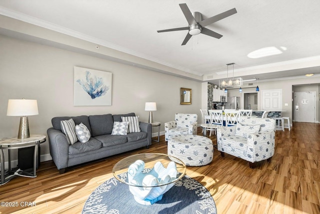 living room featuring hardwood / wood-style flooring, crown molding, and ceiling fan with notable chandelier