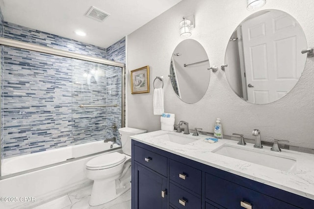 full bathroom featuring vanity, combined bath / shower with glass door, and toilet