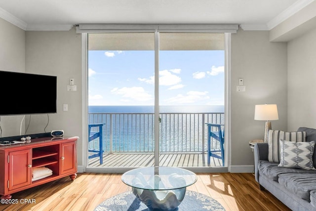 living room featuring crown molding, a water view, a wealth of natural light, and a wall of windows