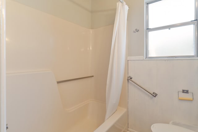 bathroom featuring a healthy amount of sunlight, shower / bathtub combination with curtain, and toilet