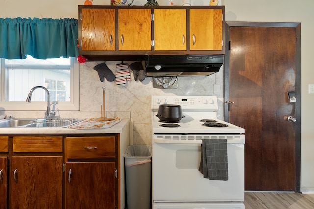 kitchen featuring electric stove, sink, and light wood-type flooring