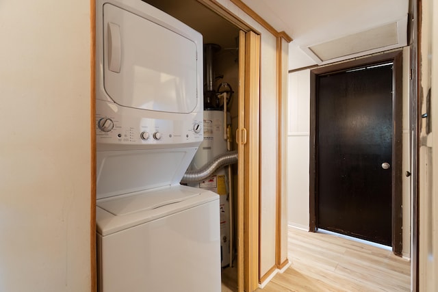 washroom with light hardwood / wood-style flooring, water heater, and stacked washer / dryer