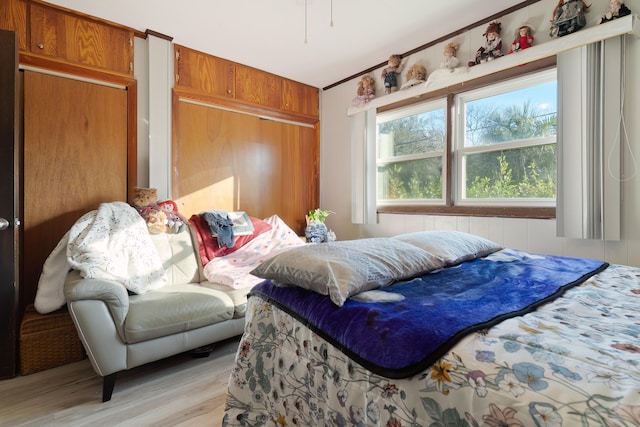 bedroom with wood walls and light wood-type flooring