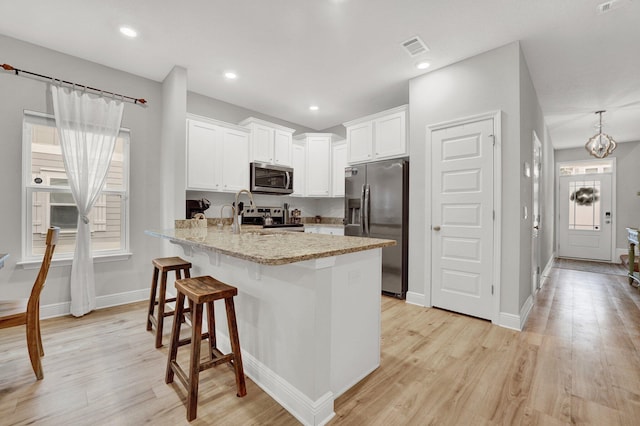 kitchen with white cabinetry, appliances with stainless steel finishes, a wealth of natural light, and light stone counters