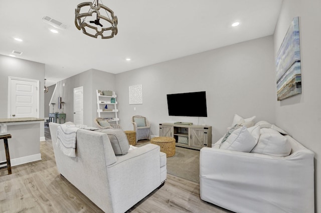 living room with light hardwood / wood-style floors and a chandelier